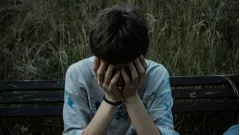 депресивний ображений підліток хлопець засмучений сумний закриває обличчя руками